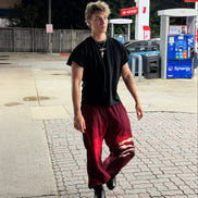 Person walking on a sidewalk at a gas station during nighttime.